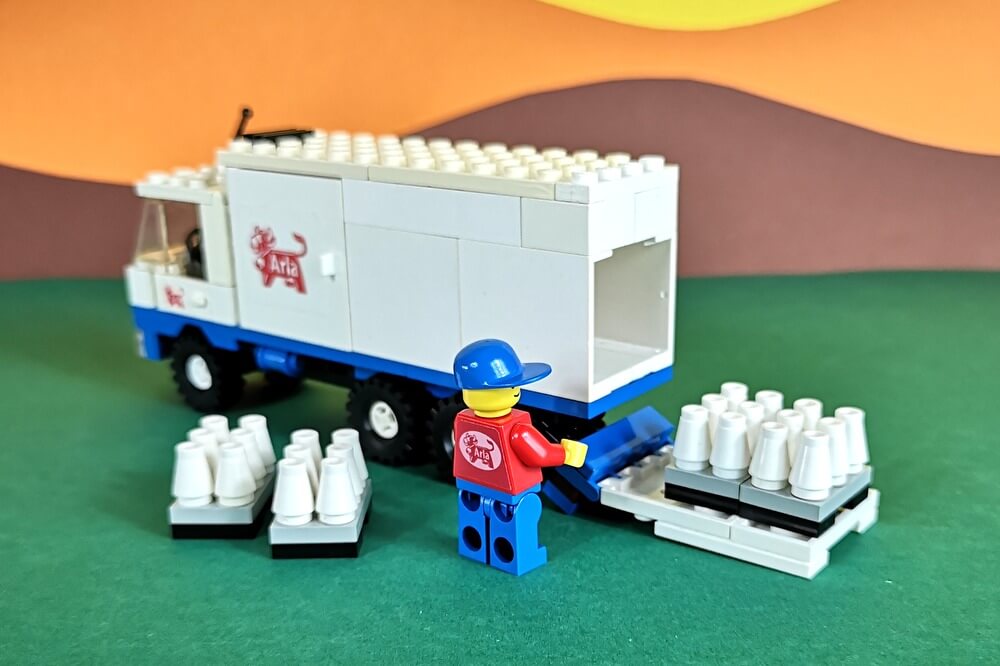 Die kleine LEGO-Minifigur belädt den Milch-Truck. Die Paletten mit den Flaschen sind aus kleinen Legosteinen gebaut.