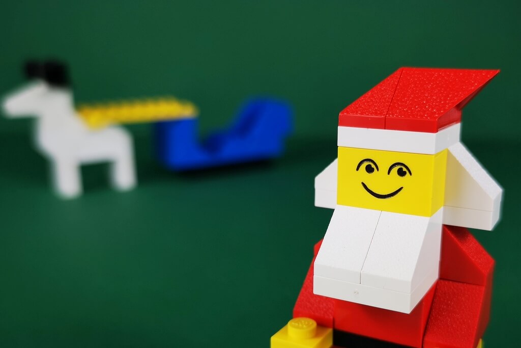 EIn LEGO-Weihnachtsmann mit bedrucktem Gesicht, das aus zwei Augen und einem Mund besteht. Das Gesicht ist sehr simpel und im Stil der 70er-Jahre.