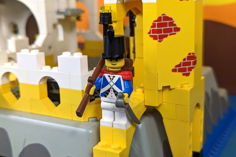 Wachposten in blauer Uniform steht vor der Lego-Festung.