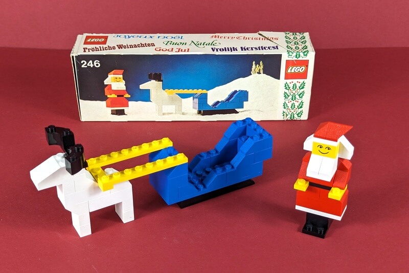 Auf dem Bild ist das erste LEGO-Weihnachtsset der Geschichte zu sehen. Vorn sieht man einen Weihnachtsschlitten mit Rentier und einen Weihnachtsmann aus LEGO-Steinen. Im Hintergrund ist die seltene originale Box von 1977 zu sehen.
