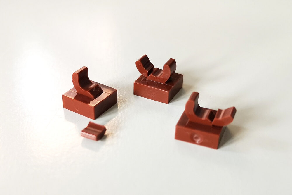 Zerbrochene LEGO-Teile in Braun mit einem gebrochenen O-Clip an der Oberseite. Das ist ein bekannter Fehler in Set 21313.