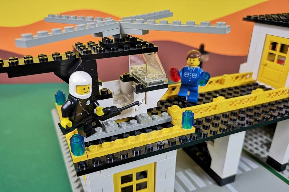 Der Hubschrauber aus Lego-Steinen ist gerade auf der Landeplattform gelandet. Der Pilot steigt aus und der Fluglotse ist im Hintergrund.