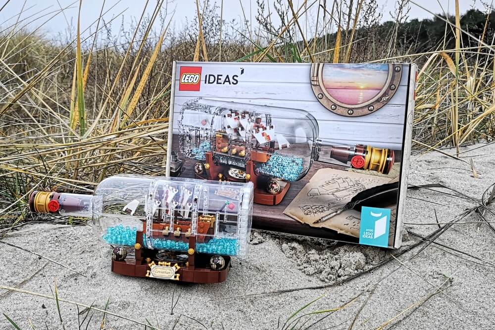 LEGO-Set 21313 aufgebaut mit Box am Strand in feinem Sand mit Strandgras.