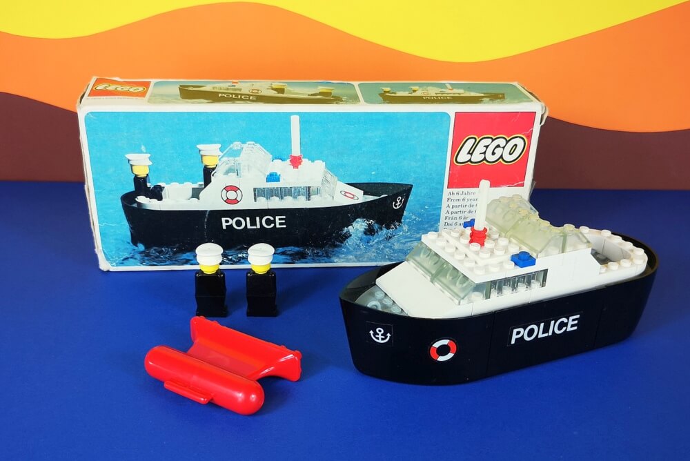 Zu sehen ist, das erste LEGO-Polizeiboot von 1976. Es kam unter der Setnummer 314 auf den Markt. Im Bild ist die seltene Originalbox zu sehen sowie das Modell und der spezielle Gewicht-Stein zum Schwimmen.