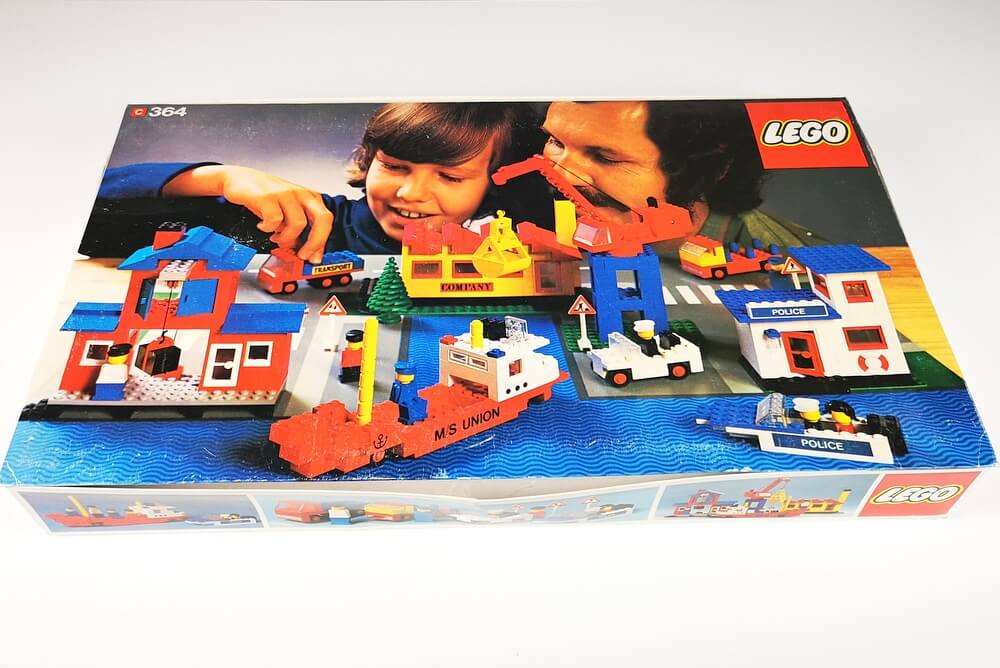 Die Vorderseite des seltenen LEGO-Kartons von Set 364. Zu sehen ist ein Vater mit seinem Junge hinter einer großen Stadtszene aus LEGO-Steinen.