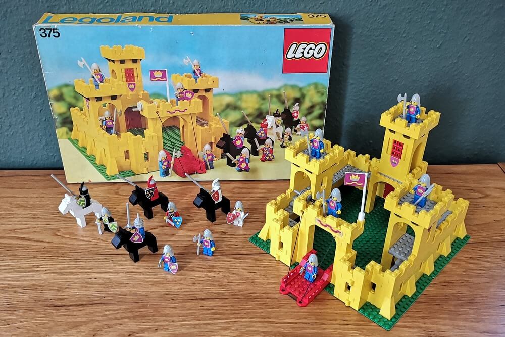 LEGO-Set 375 ist die erste LEGO-Burg im Minifigurenmaßstab und sie kam 1978 zeitgleich mit der berühmten LEGO-Minifigur auf den Markt. Auf den Bild zu sehen ist die Burg in ihren typischen gelben Bausteinen inklusive alle Figuren und die sehr seltene Original-Verpackung von 1978.