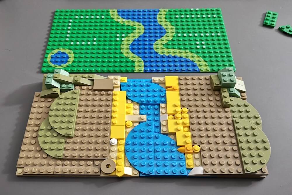 Mittelalterliche Landschaft aus Lego-Steinen mit Fluss in der Mitte.