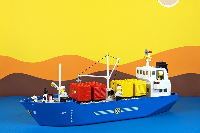 Lego-Fracht-Schiff von 1987 vor buntem Papier-Hintergrund.