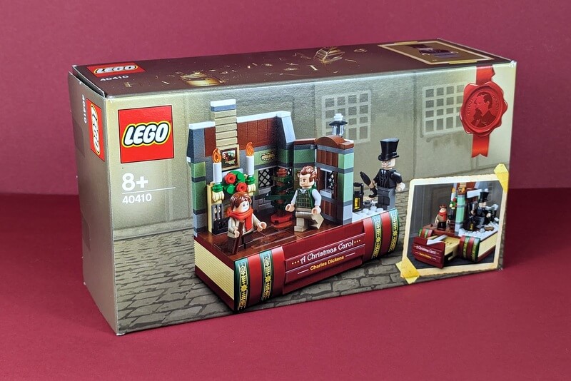 Die Box des Sets von vorn vor weihnachtlichem Hintergrund aus roter Pappe.
