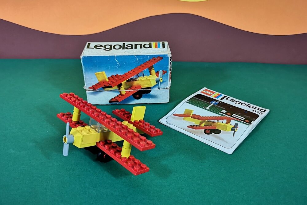 LEGO-Set 613 von 1974 mit Original-Verpackung, Bauanleitung und allen 16 Teilen zusammengesteckt. Der kleine Doppeldecker ist in den Farben Rot und Gelb designt.