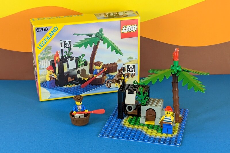 Piraten-Set 6260 aufgebaut inklusive der Originalbox von 1989 in super Zustand vor einem typischen LEGO-Hintergrund der 80er-Jahre.