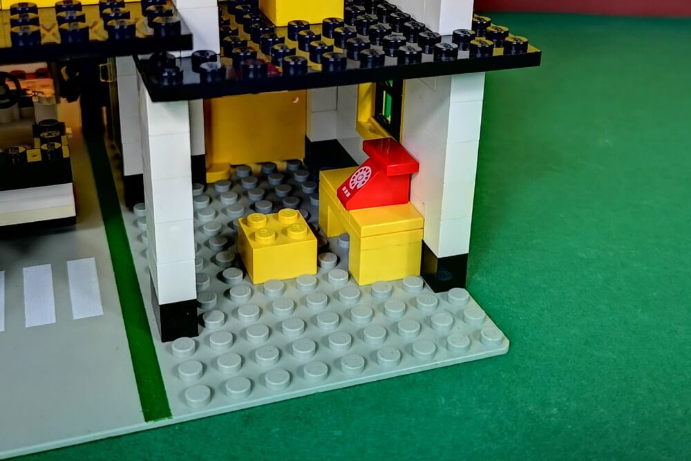 Ein Büro aus ganz einfachen Teile. Ein Schreibtisch in gelb mit Sitzhocker und ein rotes Lego-Telefon.
