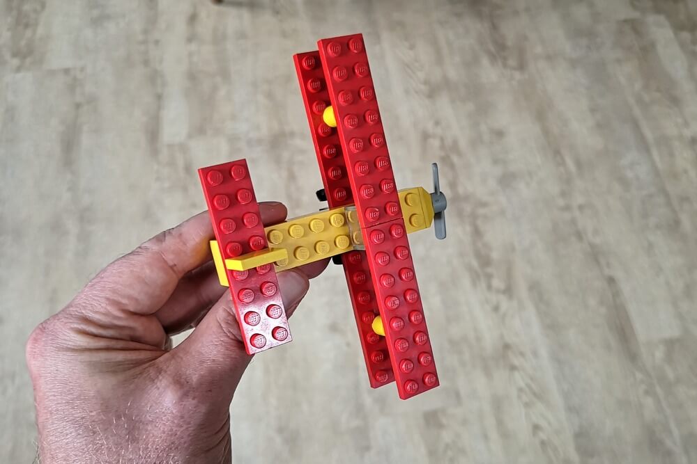 Der kleine LEGO-Flieger in der Hand beim Fliegen durch die Wohnung. EIn tolles Kinderspielzeug.