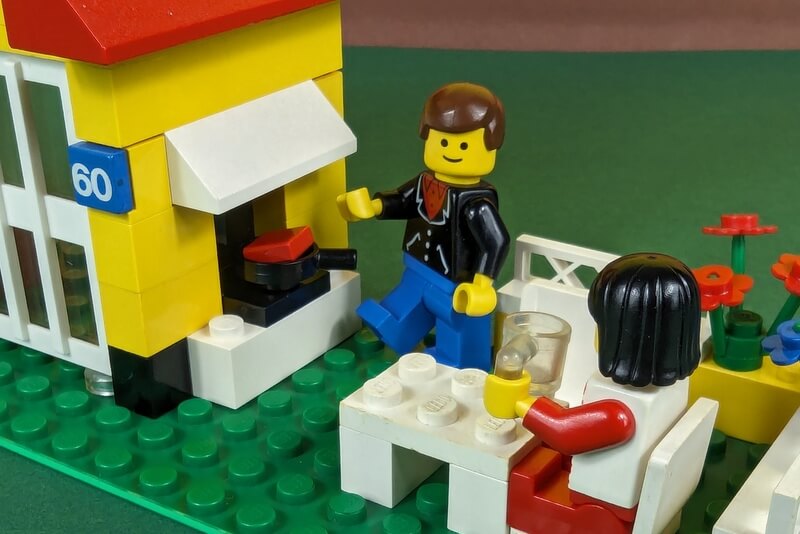 Grillszene mit zwei Lego-Figuren, einem Kamin, einer Pfanne und einem Stück Fleisch.