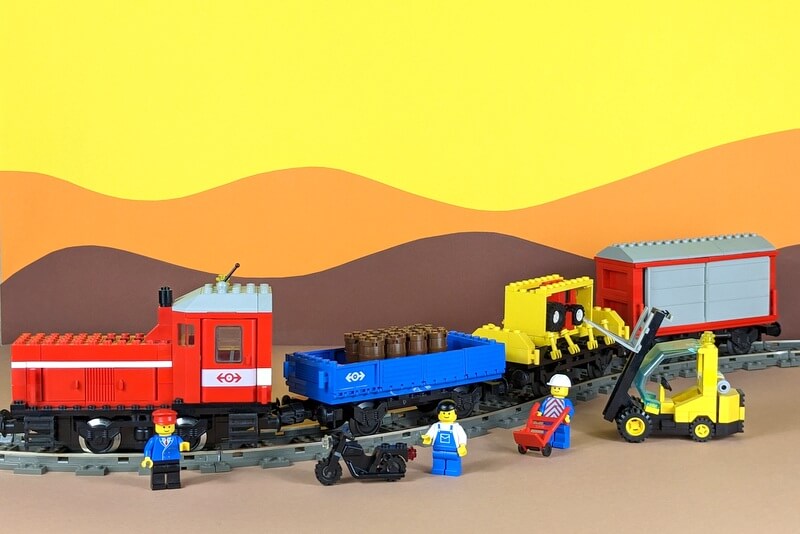 Güterzug aus Lego-Steinen aus den 90er-Jahren vor buntem Hintergrund.