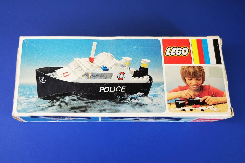 Die Rückansicht der Box vom Polizeiboot ist ebenfalls sehr einfach gestaltet. Interessant ist das Bild des kleinen Mädchens, das das Boot aus Klemmbausteinen zusammenbaut. 