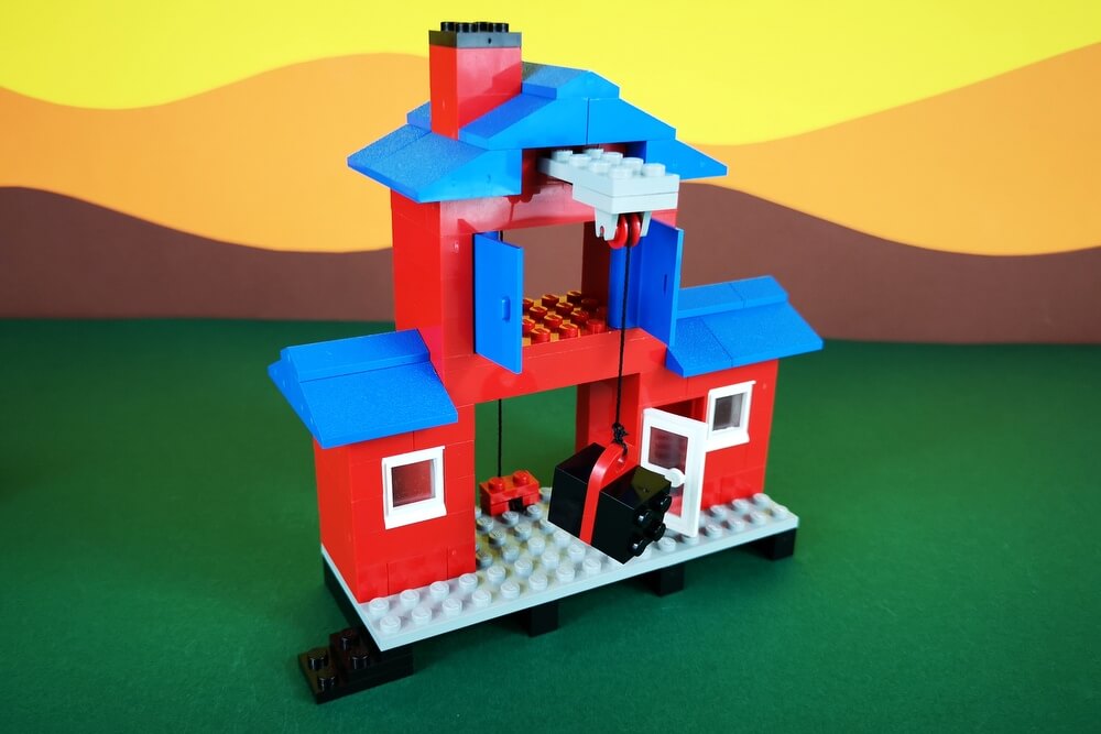Das Lagerhaus wird aush roten und blauen LEGO-Steinen gebaut und hat im oberen Bereich einen Lagerboden, der sich hinter funktionstüchtigen Türen verbirgt. 