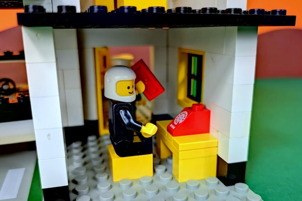 Das Legomännchen im Bild hat ein eckiges Lego-Teil in der Hand, das wie ein Telefonhörer wirkt. 