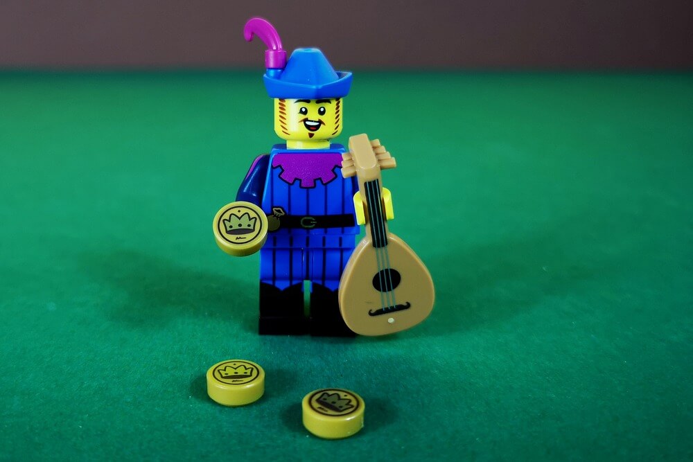 Der Barde der LEGO-Minifiguren-Serie 22 aus dem Jahr 2022. Er trägt einen blauen Hut und blaue Kleidung mit pinkfarbenen Details plus eine Gitarre.