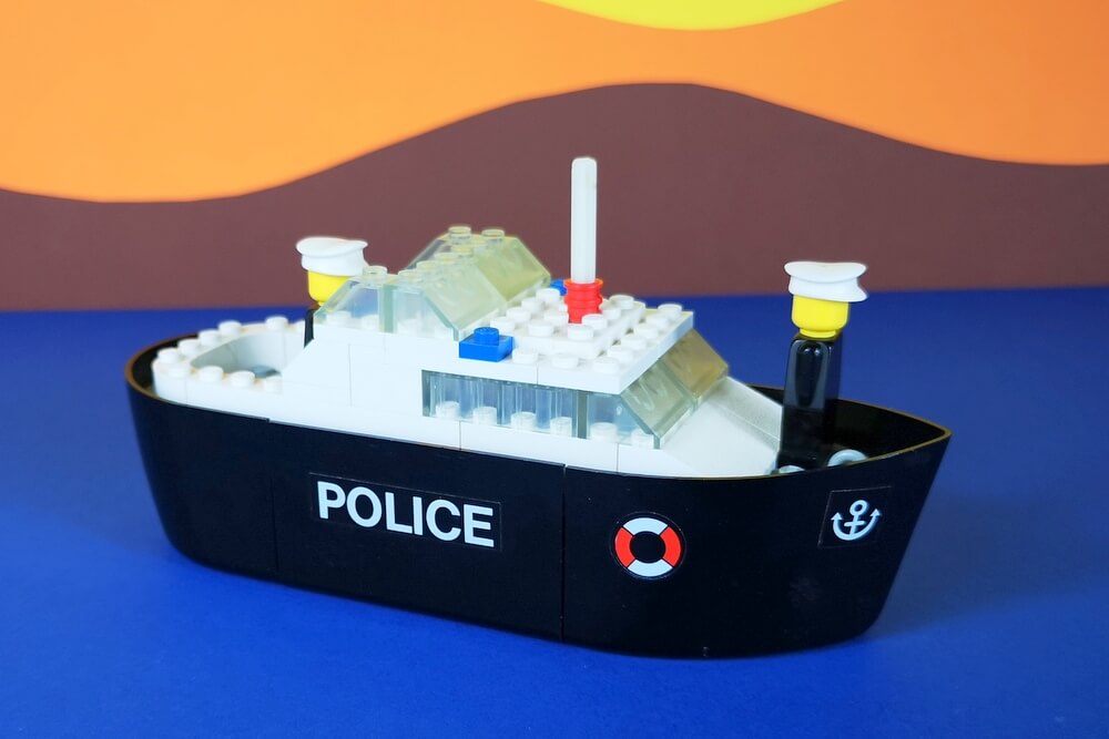Das erste Polizeiboot der Lego-Geschichte vor einem klassischen Hintergrund aus bunter Pappe, so wie die Fotos früher auch in Katalogen zu sehen waren.