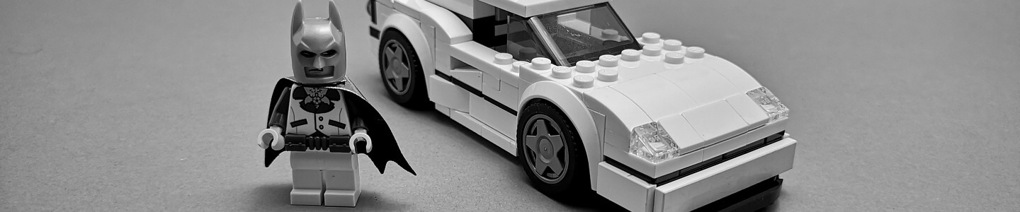 Auf dem Bild sieht man einen Ferrari F40 aus LEGO-Steinen. Das Modell stammt aus der Speed-Champions-Reihe. Neben dem Rennwagen steht eine Batman-Minifigur mit Disko-Outfit.