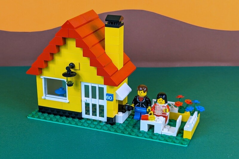Das Haus mit den Figuren vor einem zeitlich passenden bunten Hintergrund, wie er typisch für die damalige Zeit bei Lego war.