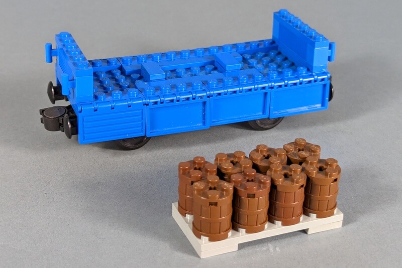 Zug-Waggon aus Lego-Steinen mit Fässern, die gerade entladen werden.