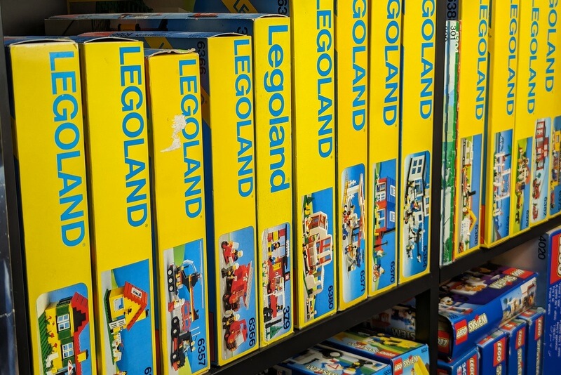 Ein Regal in dem ganz viele alte Lego-Kartons nebeneinander stehen.