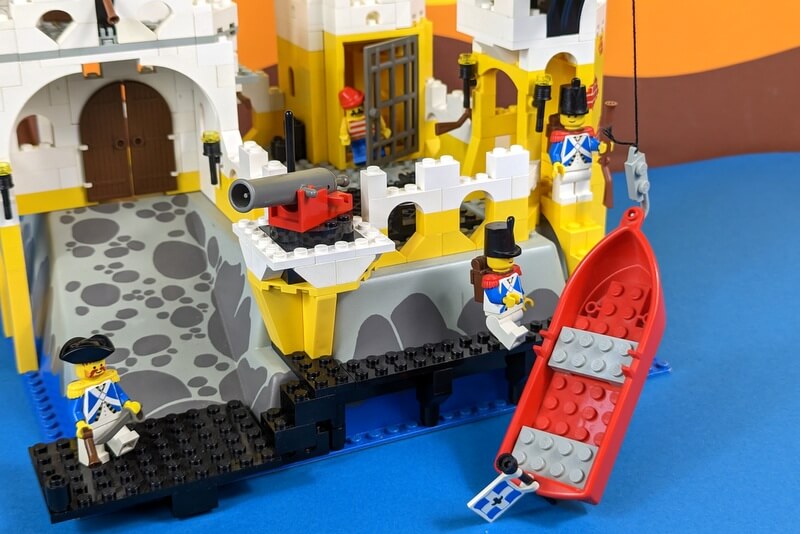 Zwei Minifiguren ziehen ein Ruderboot mit einem Lastenkran an Land. 