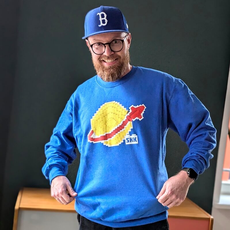 Sebastian Beintker trägt einen Pullover mit dem klassischen Space-Logo, wie es Lego in den 80er-Jahren verwendet hat.